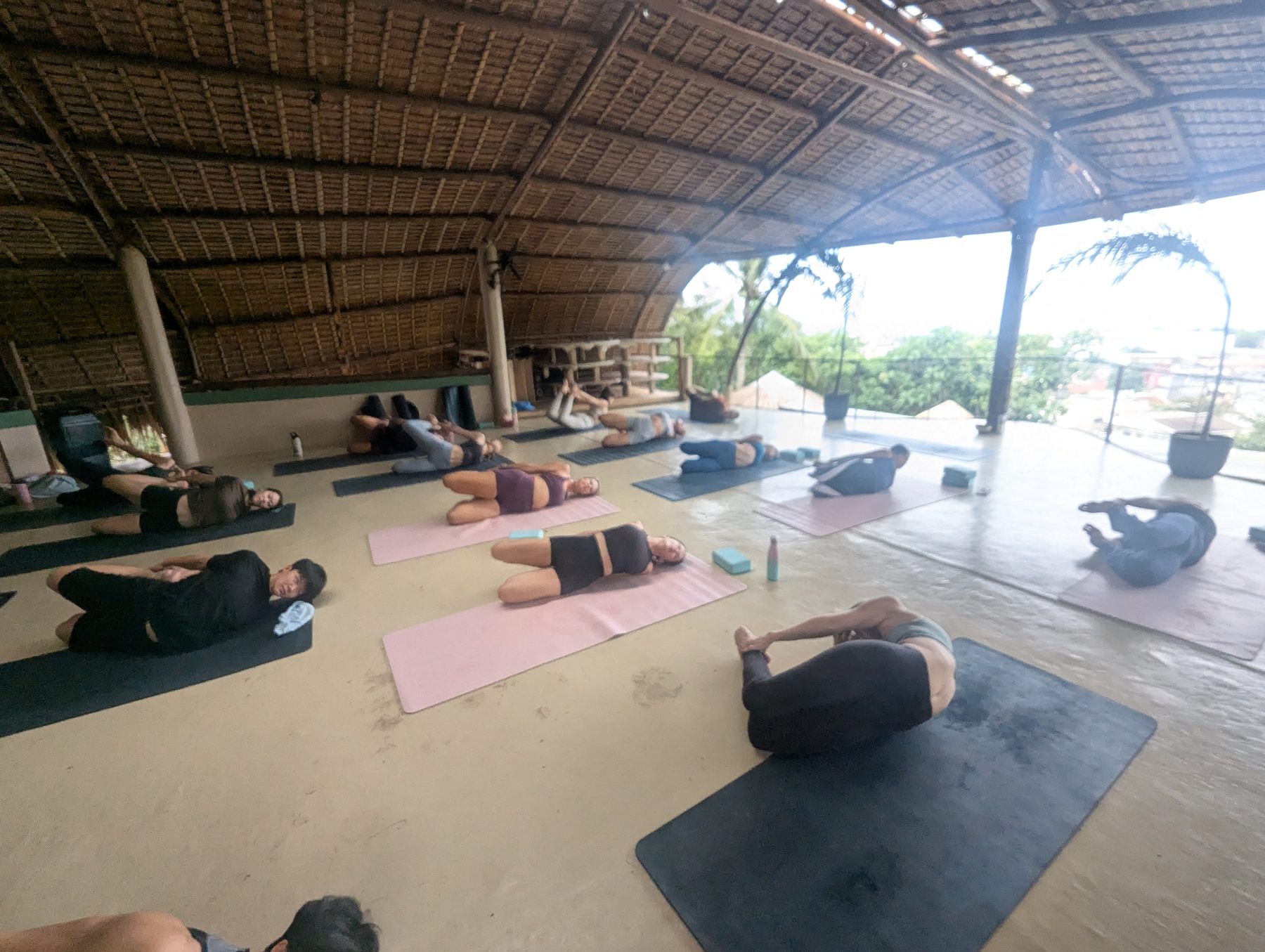 A group in restorative poses on mats under an open-air bamboo studio