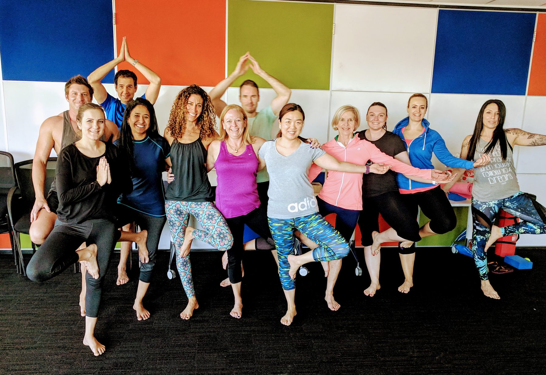 A large corporate team in tree pose during an office yoga session