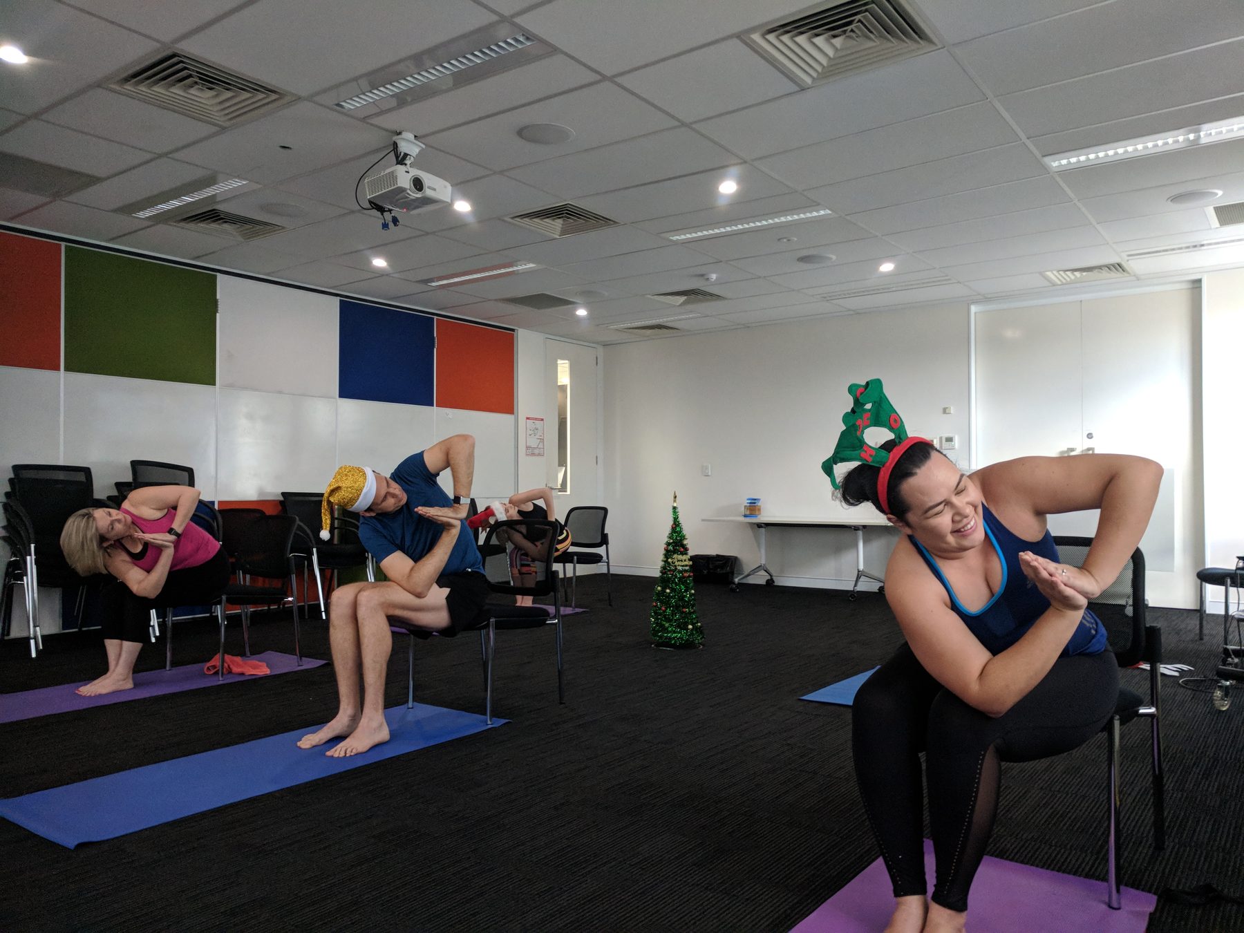 A small group doing seated chair yoga in festive headwear