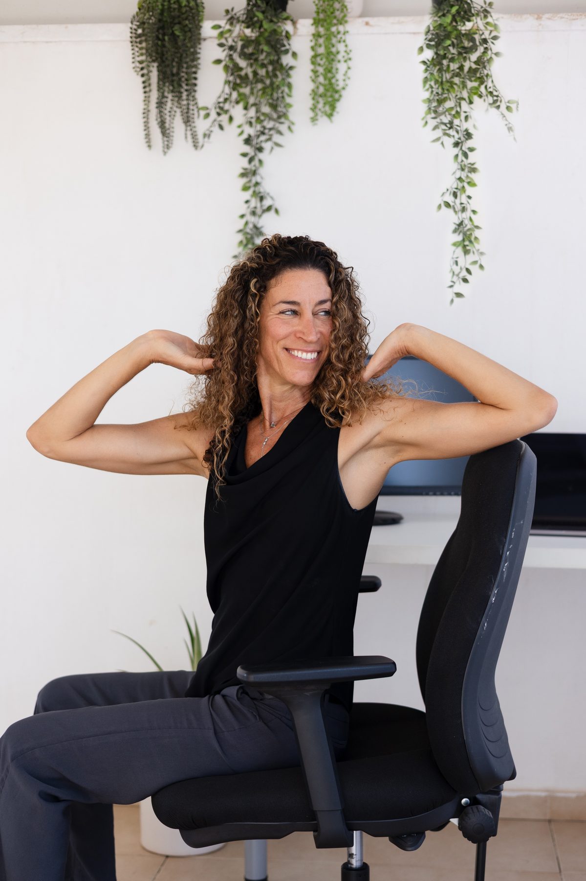 Shani stretching her neck and shoulders while seated at a desk