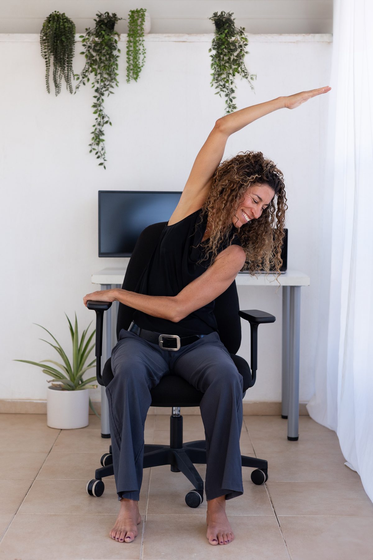 Shani Abergil stretching, smiling, in her home studio